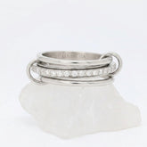 Zilveren Neo fidget ring van RVS opgebouwd uit drie ringen met een roterende middelste band vol zirkonia steentjes, gepresenteerd op een witte steen.