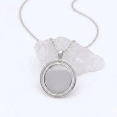 Zilveren Oracle fidget ketting van RVS met een roterend hangerontwerp, elegant gepresenteerd op een witte steen.