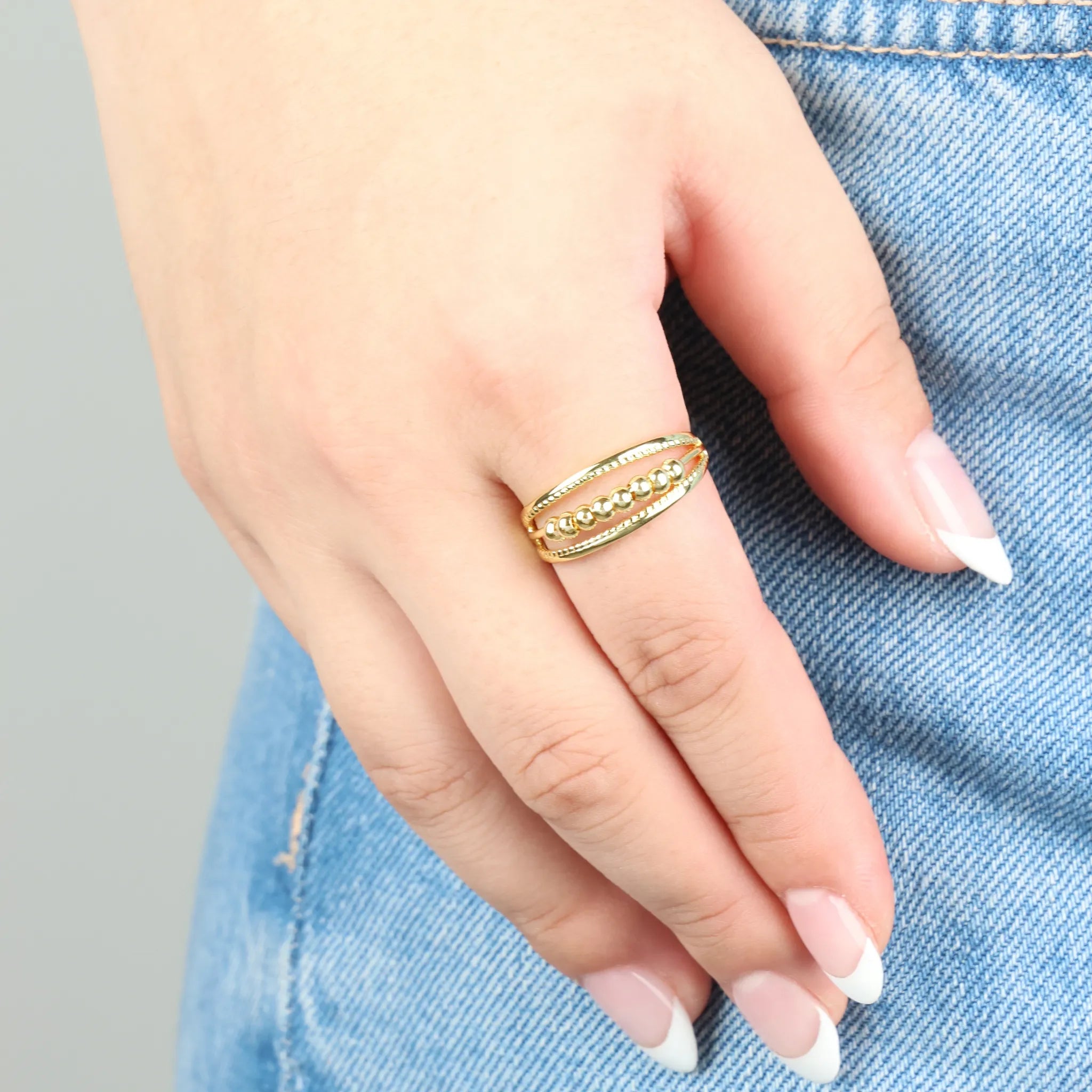 Vrouw draagt goudkleurige Pendulum anxiety ring – helpt ontspannen en stress verminderen