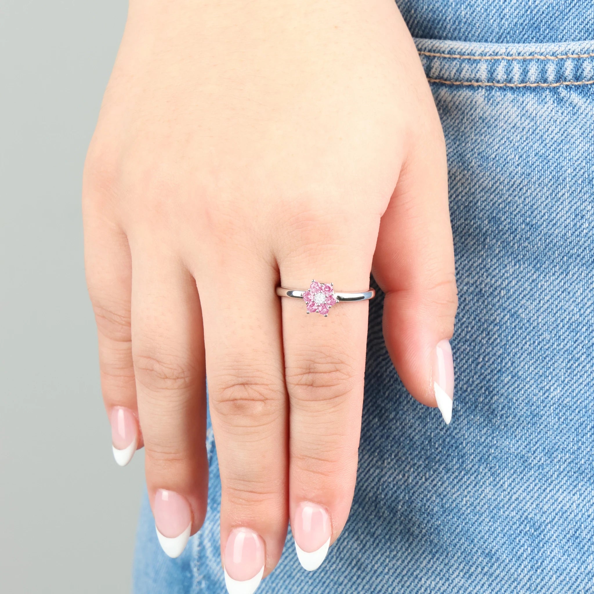 Close-up van de Petal stress ring met roze kristallen bloemblaadjes gedragen op een jeans.