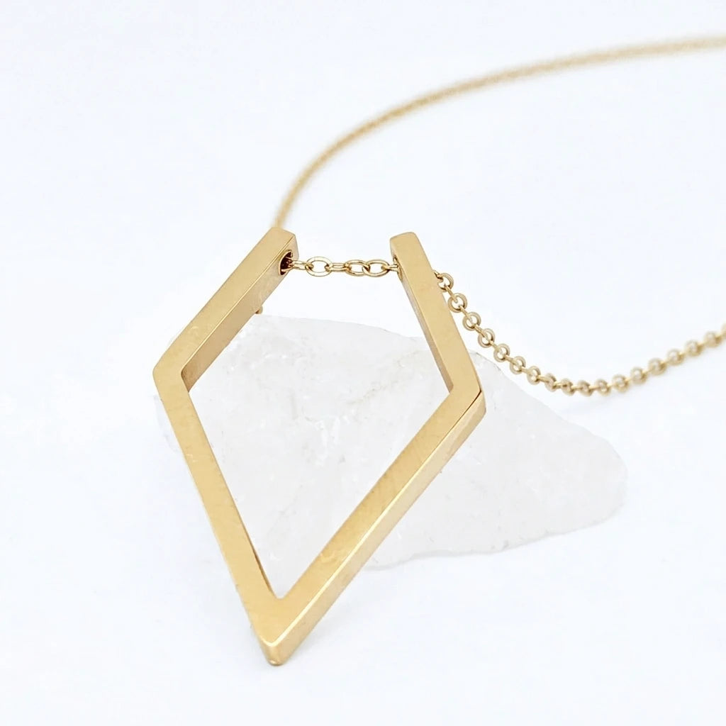 Gouden Ring Keeper ketting van RVS met een praktische en stijlvolle ring holder hanger, rustend op een witte steen.