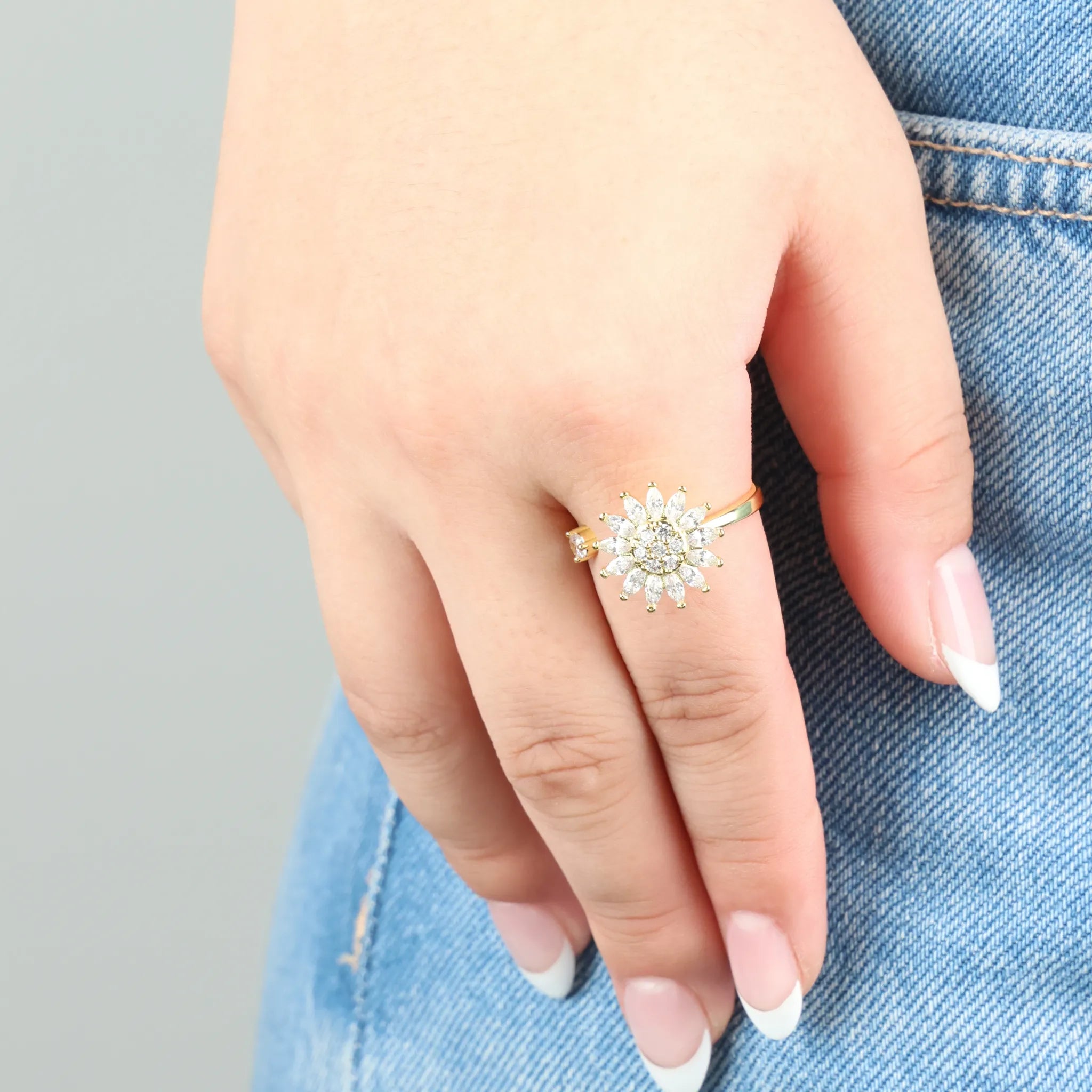 Sunflower anxiety ring in goud gedragen op hand met spijkerbroek