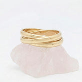 Gouden Trinity fidget ring van RVS opgebouwd uit drie in elkaar vallende, rollende ringen, elegant rustend op een witte steen.