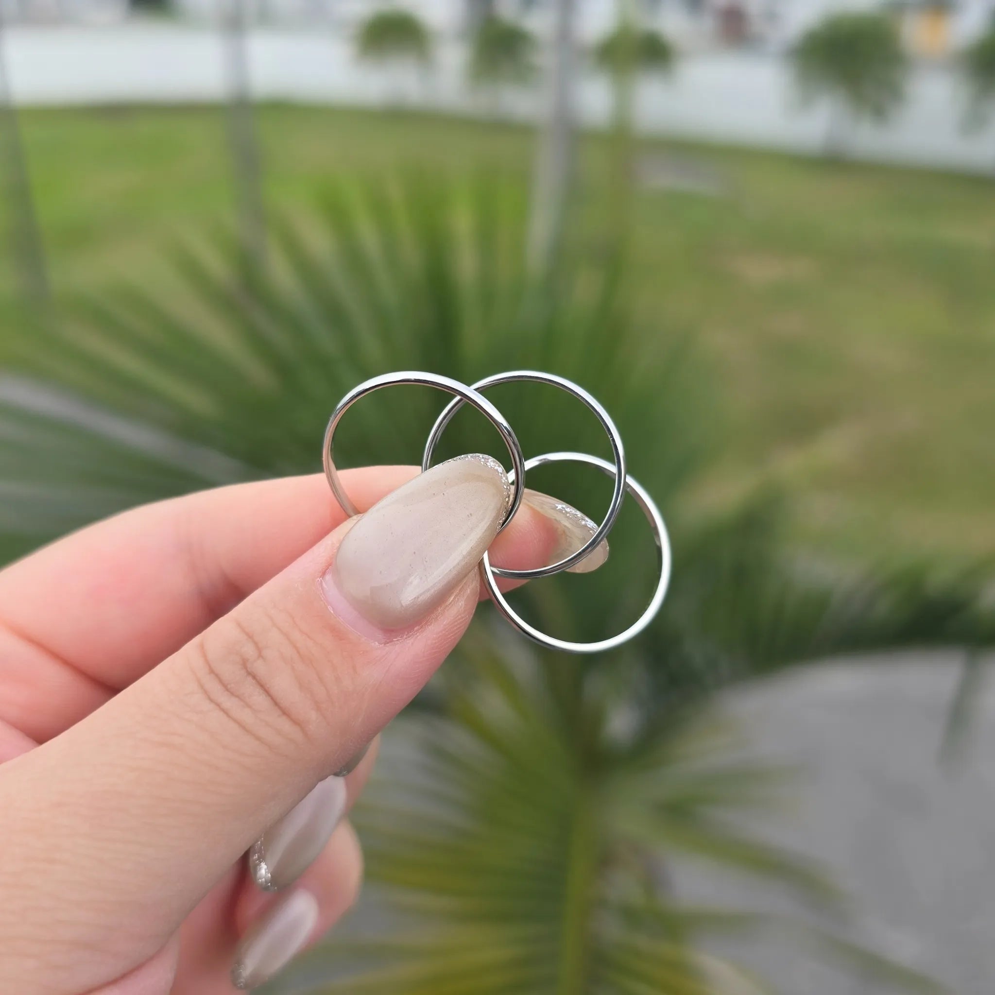 Hand houdt de zilverkleurige Unity fidget ring vast met drie losse, in elkaar verstrengelde ringen – rustgevend design van Luminora.