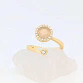 Close-up van gouden Opal wellness ring met opaalsteen en kristalrand – verstelbare ring die balans en sereniteit uitstraalt