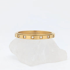 Close-up van gouden Raya wellness ring van stainless steel met kristallen in vierkante zettingen – symbool van balans en kalmte