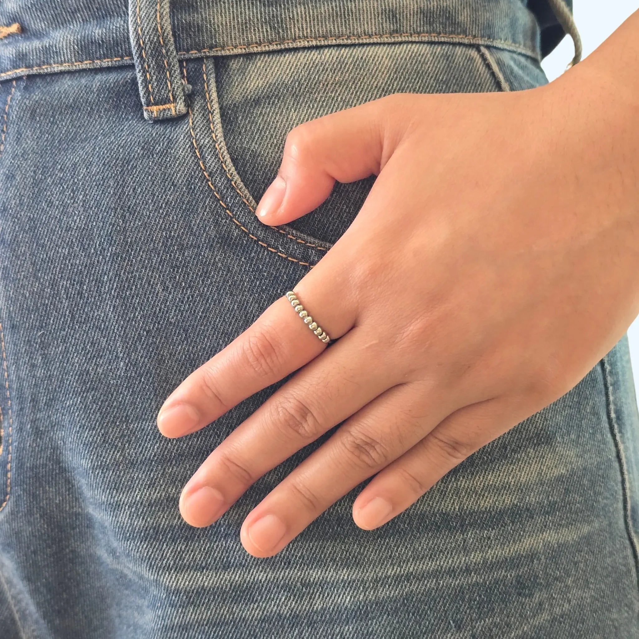 Zilveren Classic Bead anxiety ring van RVS met draaibare kralen om de vinger, gedragen bij een casual blauwe spijkerbroek.