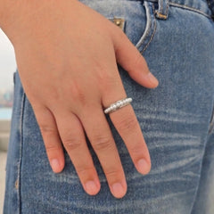 Zilveren Perla anxiety ring van RVS met een draaiende parelband om de vinger, gedragen bij een casual blauwe spijkerbroek.