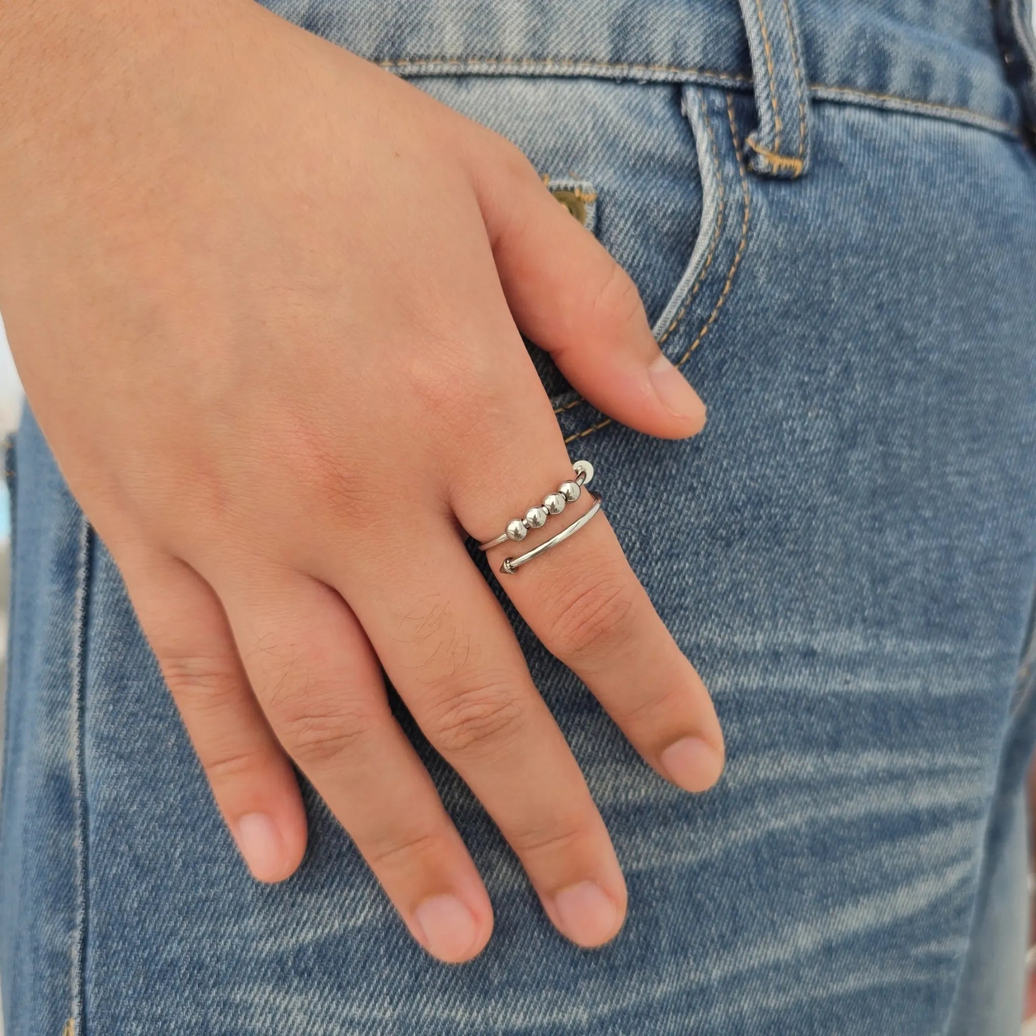 Zilveren Punta Bead anxiety ring van RVS met losse kralen en stoer spijkerdesign om de vinger, gedragen bij een casual blauwe spijkerbroek.