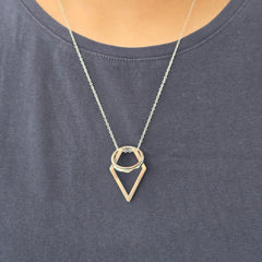 Detailopname van de zilveren Ring Keeper ketting gedragen over een blauw shirt, met een ring veilig ingehangen aan de RVS hanger.