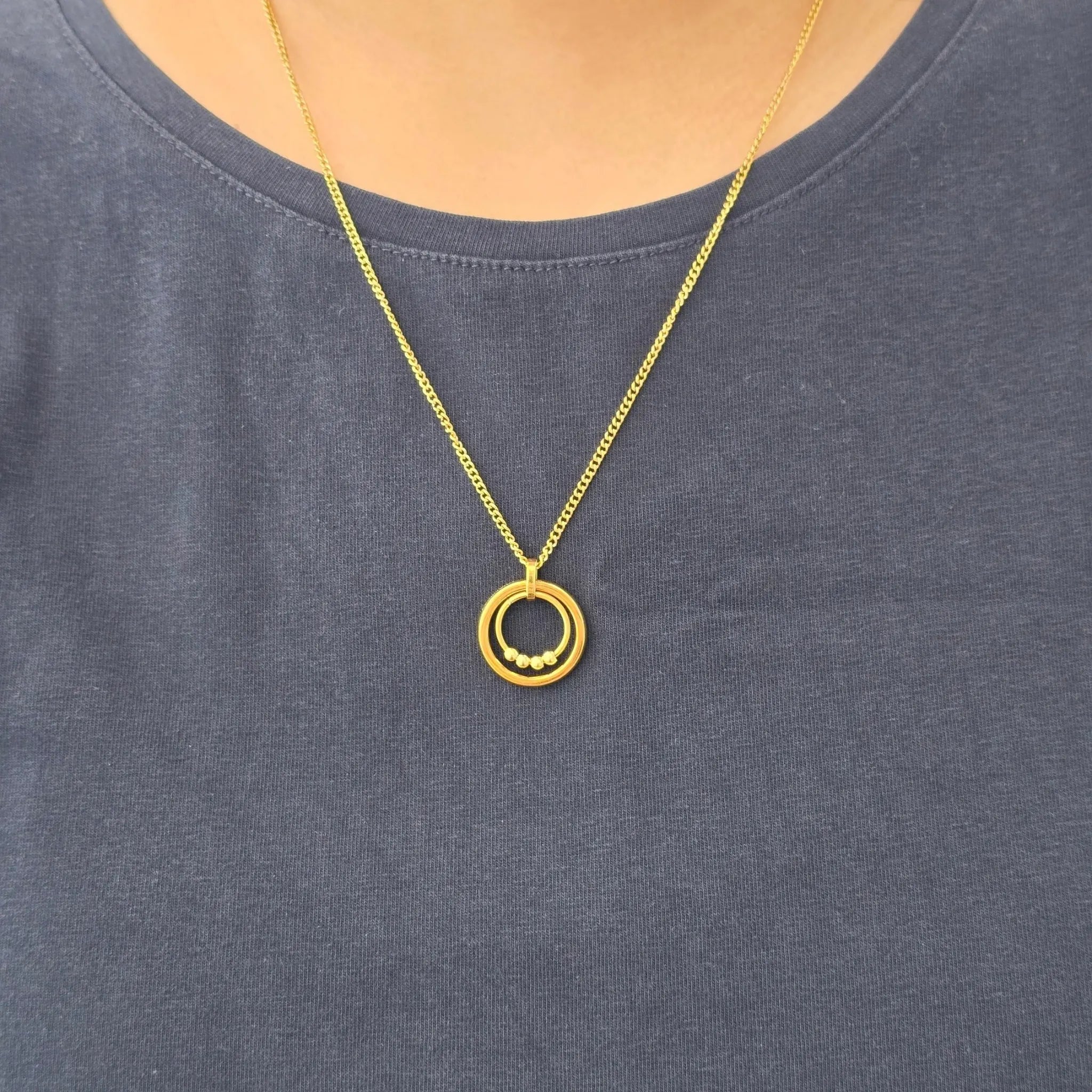 Gouden Bead Ketting van RVS met beweegbare kralen gedragen om de hals bij een blauw shirt – stijlvolle anxiety ketting voor dagelijks gebruik.
