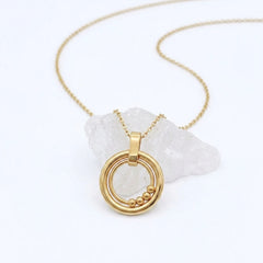 Bead Ketting in goud van RVS met beweegbare kralen op een witte steen – stijlvolle fidget ketting voor rust en ontspanning.