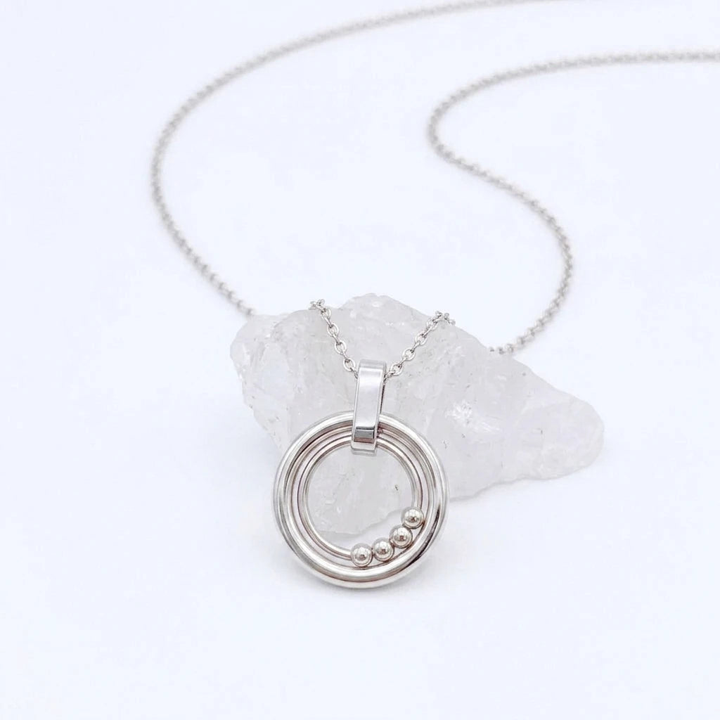 Bead Ketting in zilver van RVS met beweegbare kralen op een witte steen – elegante fidget ketting voor rust en ontspanning.
