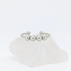Zilveren Core Bead anxiety ring ontworpen als subtiele fidget ring, geplaatst op een witte kwartssteen.