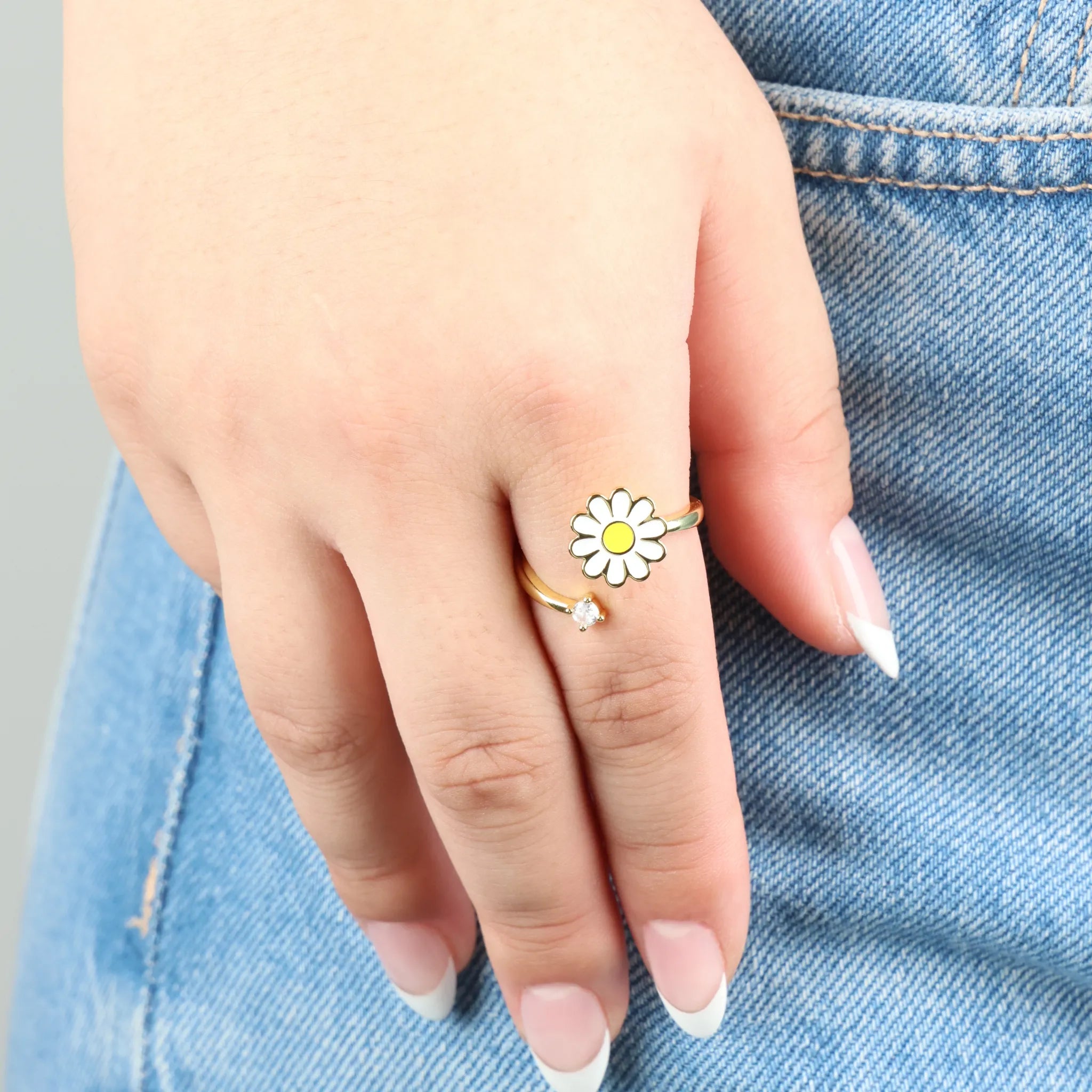 Daisy anxiety ring in goud gedragen op hand met spijkerbroek