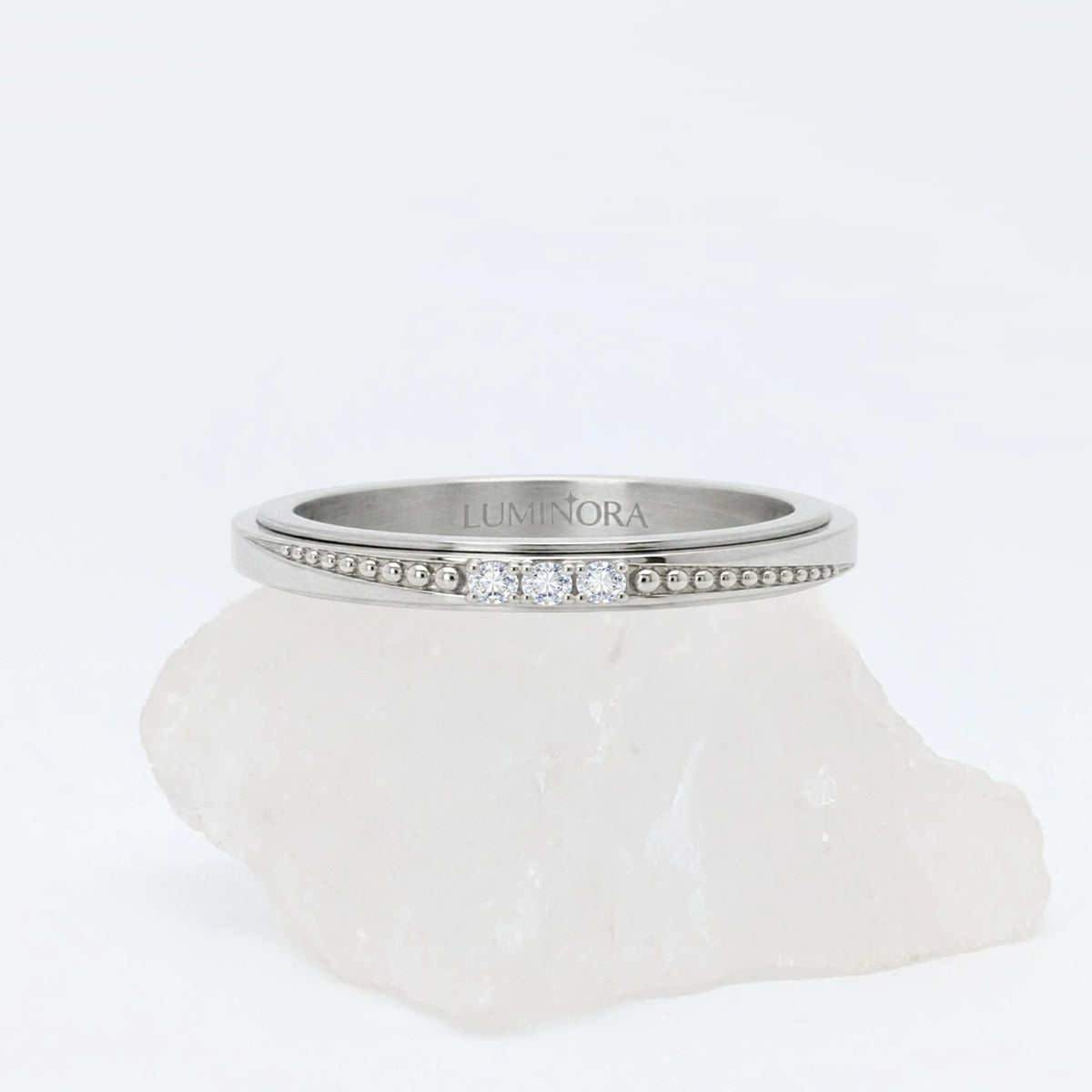 Zilveren Elara anxiety ring ontworpen als elegante fidget ring, geplaatst op een witte kwartssteen.