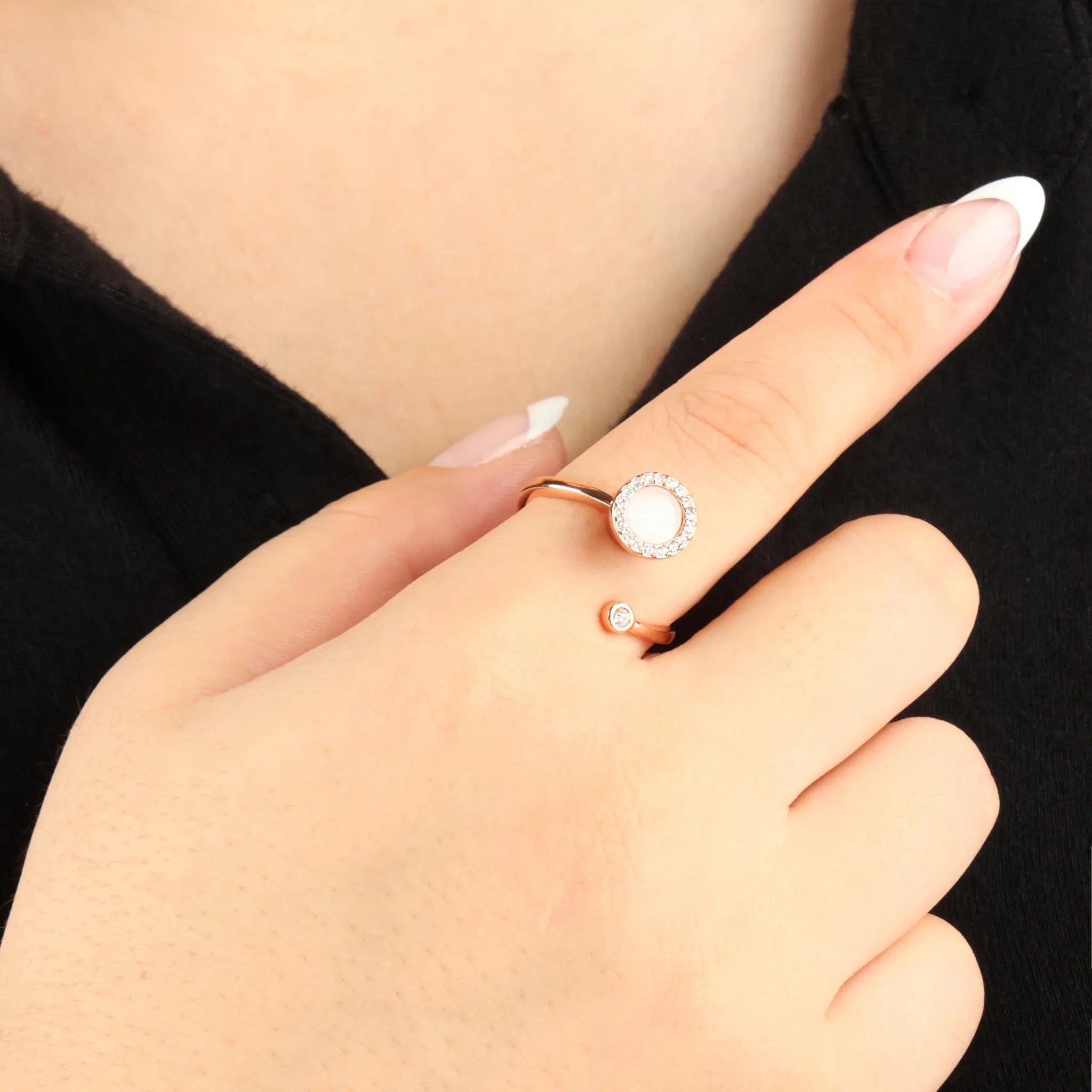 Roségouden Opal fidget ring met fonkelende kristallen en ronde opaalsteen, gedragen bij zwarte top – elegant hulpmiddel tegen stress