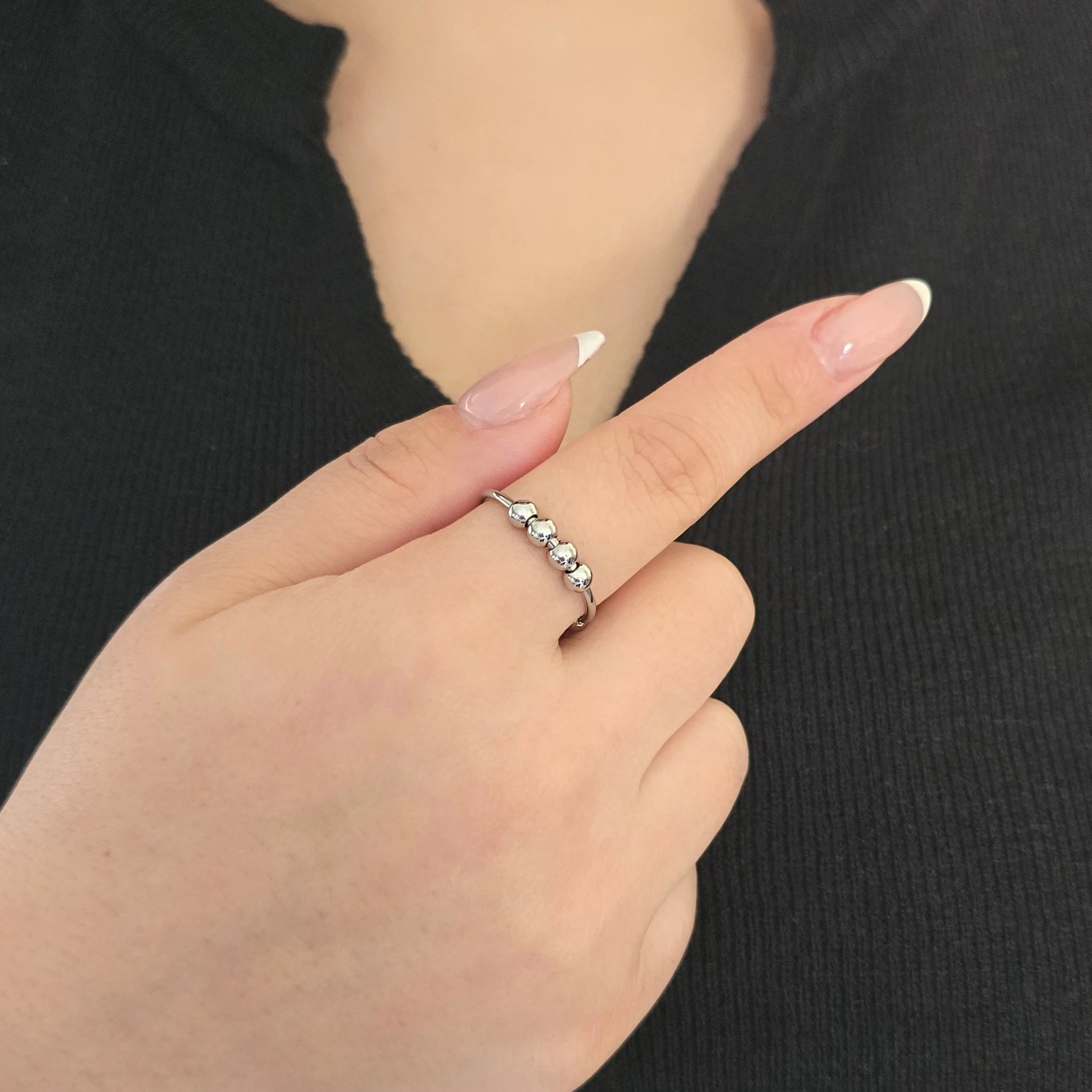 Elegante zilveren fidget ring met beweegbare kralen, gedragen door een model met een zwart topje.