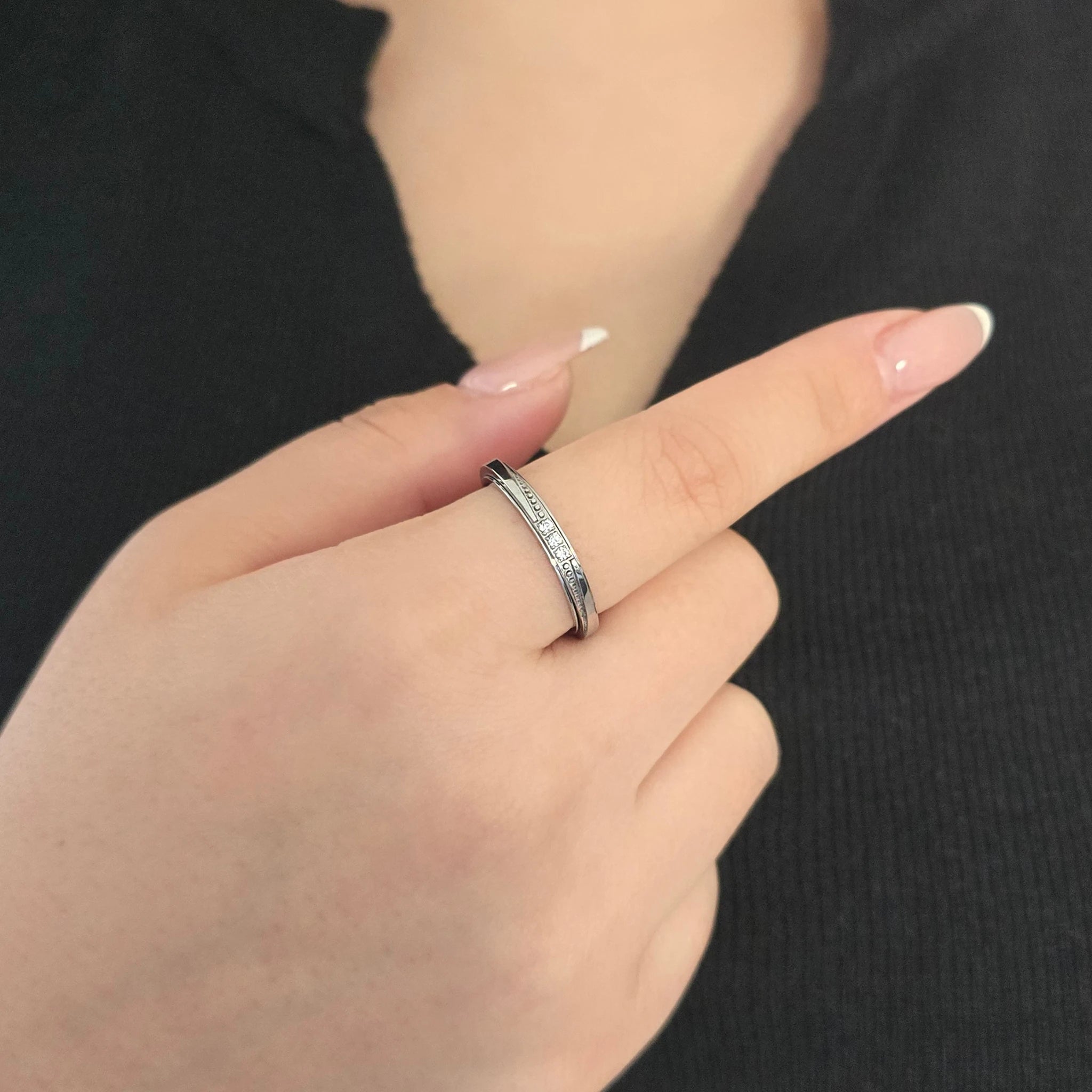 Elegante zilveren fidget ring met fonkelende steentjes, gedragen door een model met een chique zwart topje.