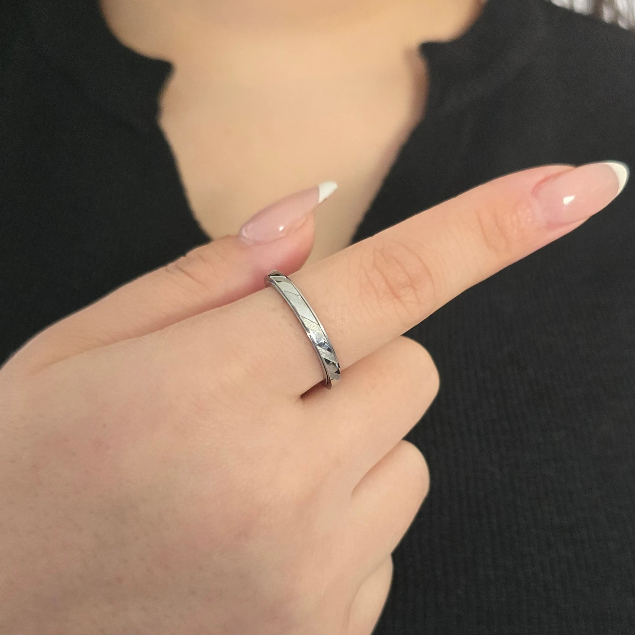 Elegante zilveren Prism fidget ring met strakke geometrische lijnen, gedragen aan de wijsvinger van een model met een zwart topje.