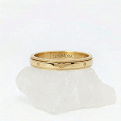 Gouden Fortuna fidget ring van RVS met een draaibaar klaver patroon, elegant rustend op een witte steen