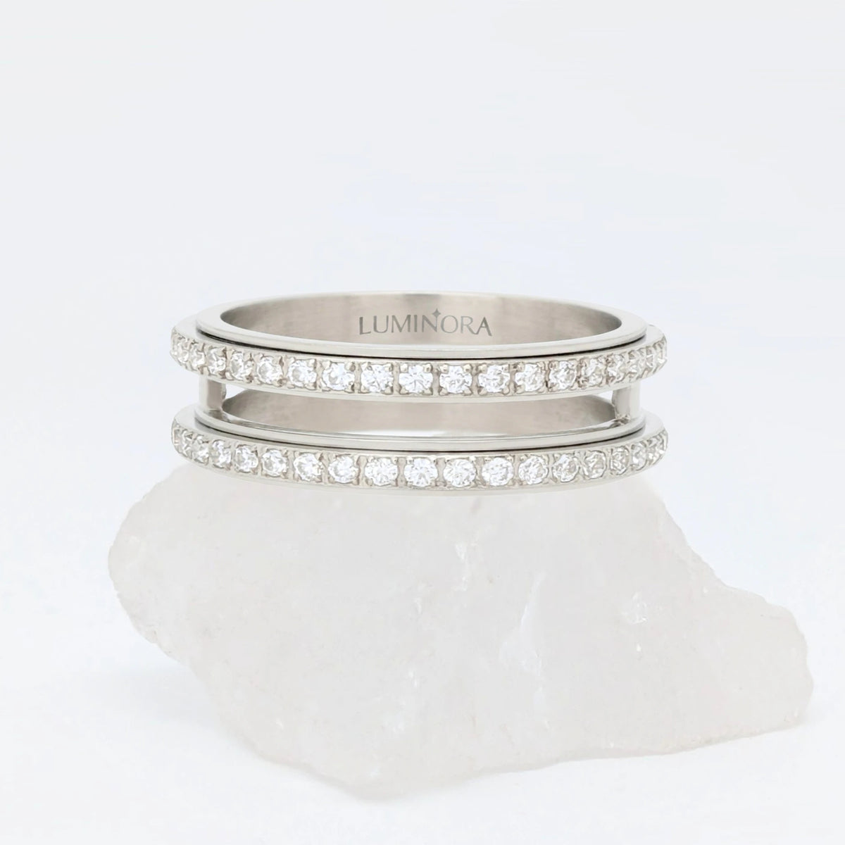 Zilveren Gemini anxiety ring ontworpen met een elegante dubbele rij steentjes, geplaatst op een witte kwartssteen.