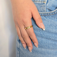 Hand van een vrouw in een casual blauwe spijkerbroek met een elegante gouden Clover anti-stress ring met een klavertje vier om haar vinger.