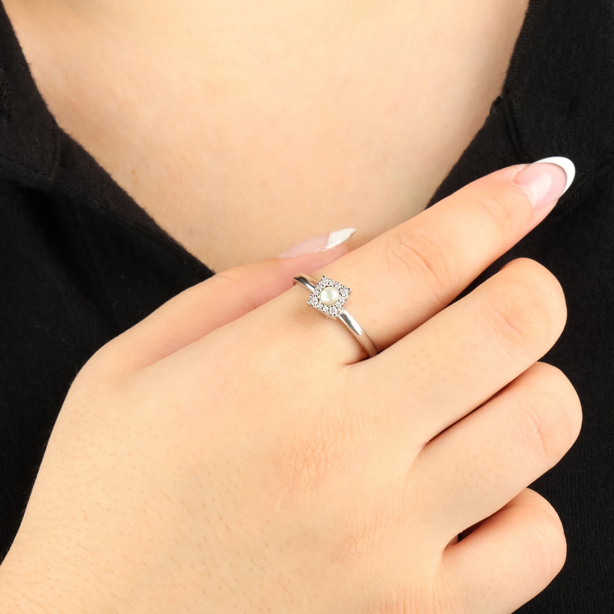 Zilveren Halo anxiety ring met een subtiel draaimechanisme om de vinger tegen een contrasterend zwart shirt.