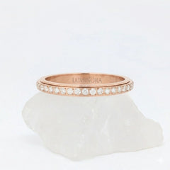 Roségouden Haven fidget ring van waterproof roestvrij staal, afgewerkt met een roterende band vol schitterende steentjes, gepresenteerd op een witte steen.