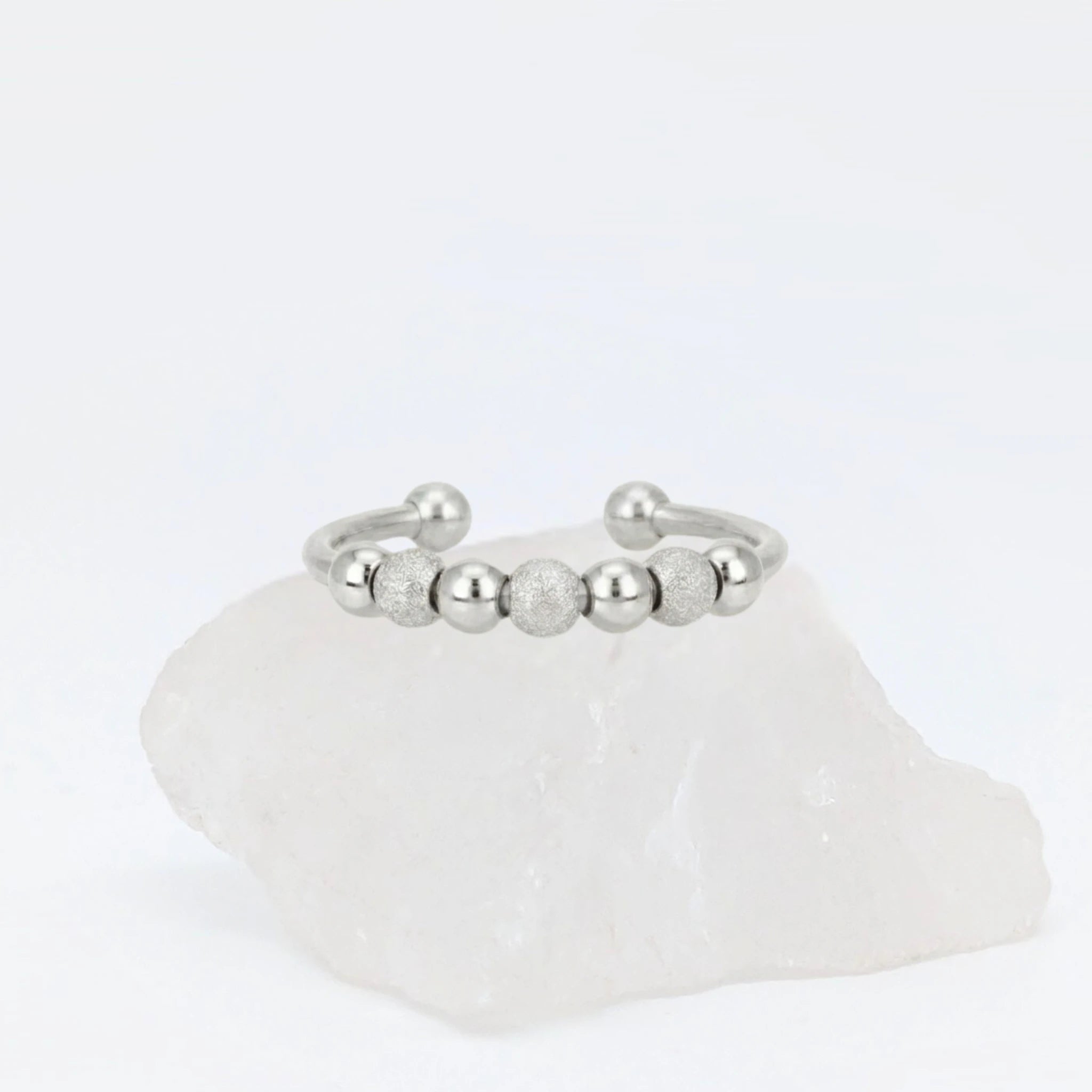 Zilveren Ivy Bead anxiety ring ontworpen met elegante kraaltjes, geplaatst op een witte kwartssteen.