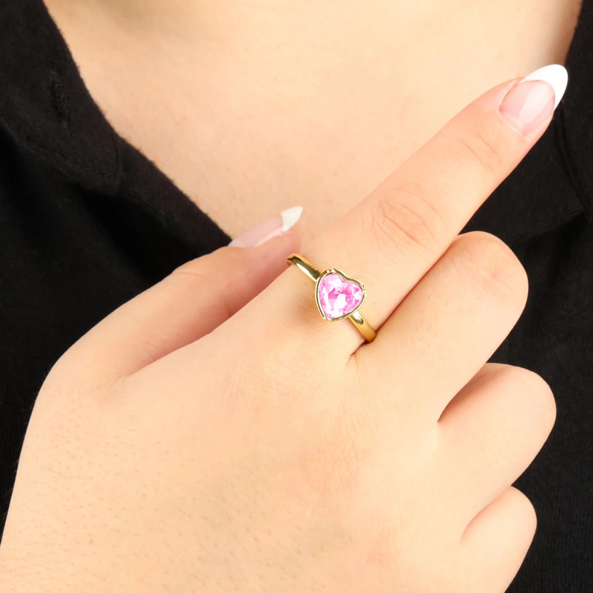Gouden Love anxiety ring met een draaiend roze hartvormig element, gefotografeerd bij een zwart shirt.