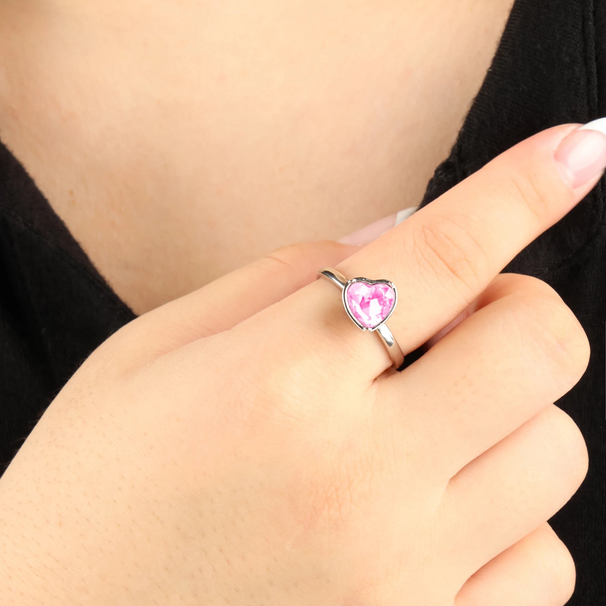 Zilveren Love anti-anxiety ring met een draaiend roze hartje om de vinger tegen een zwart shirt.