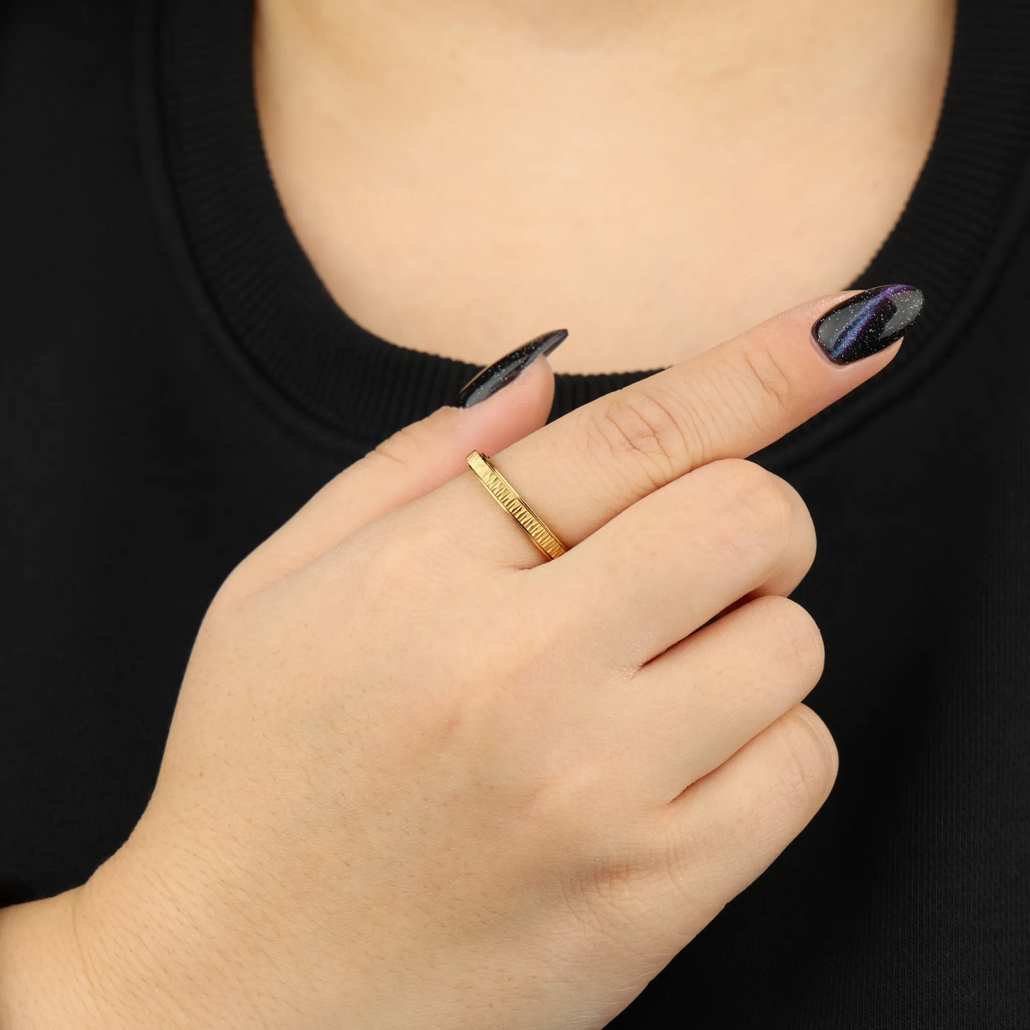 Gouden Mello anxiety ring gedragen aan vrouwenhand voor borst met zwart shirt – Luminora
