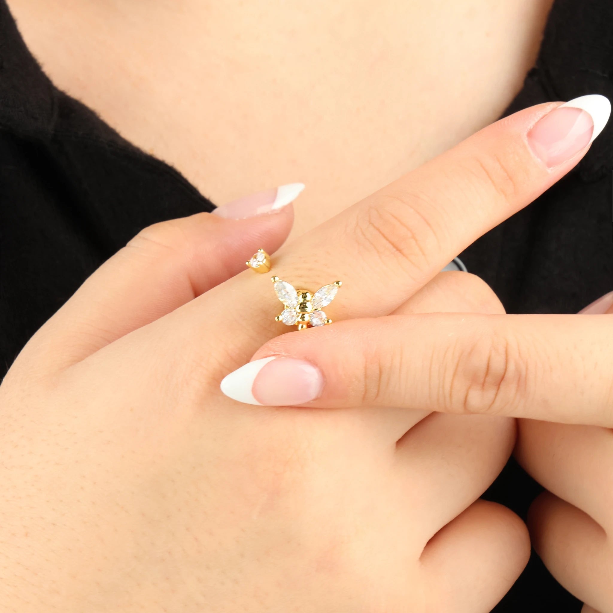 Gouden Nabi anxiety ring met een draaiend vlinderelement om de vinger gefotografeerd bij een zwart shirt.