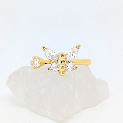 Gouden Nabi fidget ring met een elegante sprankelende vlinder liggend op een witte ruwe steen.