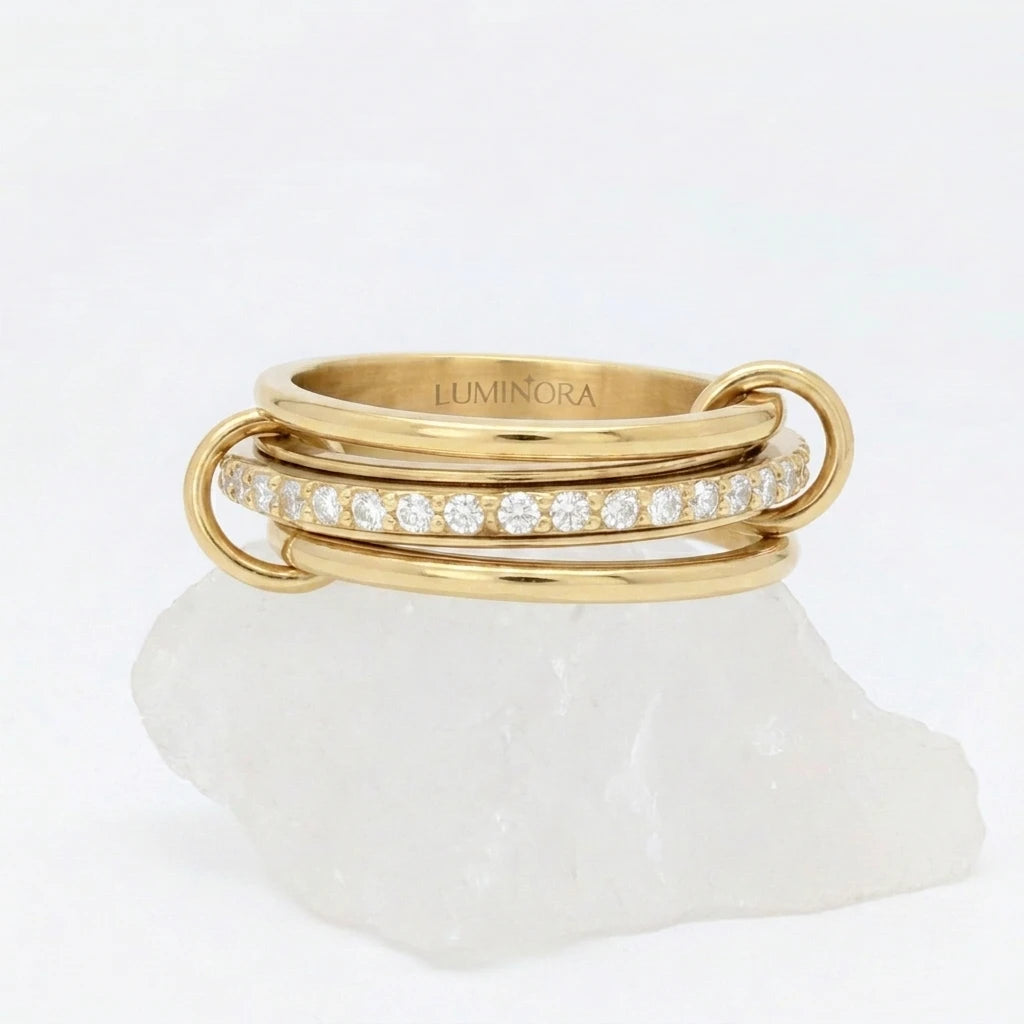 Gouden Neo fidget ring van RVS met een opvallend design van drie gestapelde ringen en glimmende steentjes, elegant rustend op een witte steen.