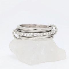 Zilveren Neo fidget ring van RVS opgebouwd uit drie ringen met een roterende middelste band vol zirkonia steentjes, gepresenteerd op een witte steen.