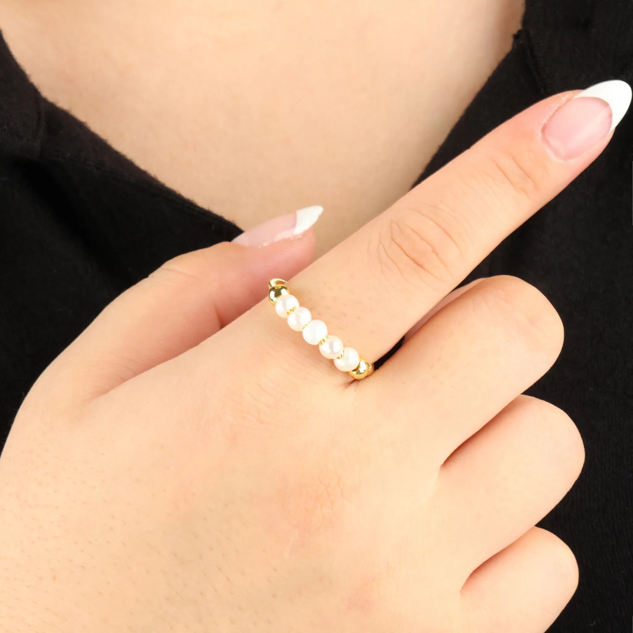 Gouden Pearl fidget ring met witte parels gedragen bij zwart shirt