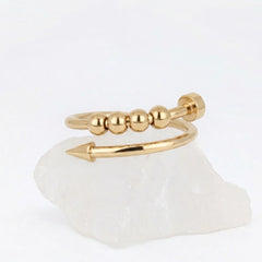 Gouden Punta Bead fidget ring van RVS met een uniek gebogen spijkerontwerp en roterende kralen, gepresenteerd op een witte steen.