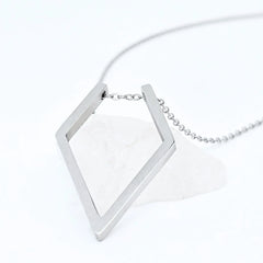 Zilveren Ring Keeper ketting van RVS met een ruitvormige hanger voor ringen, elegant gepresenteerd op een witte steen.
