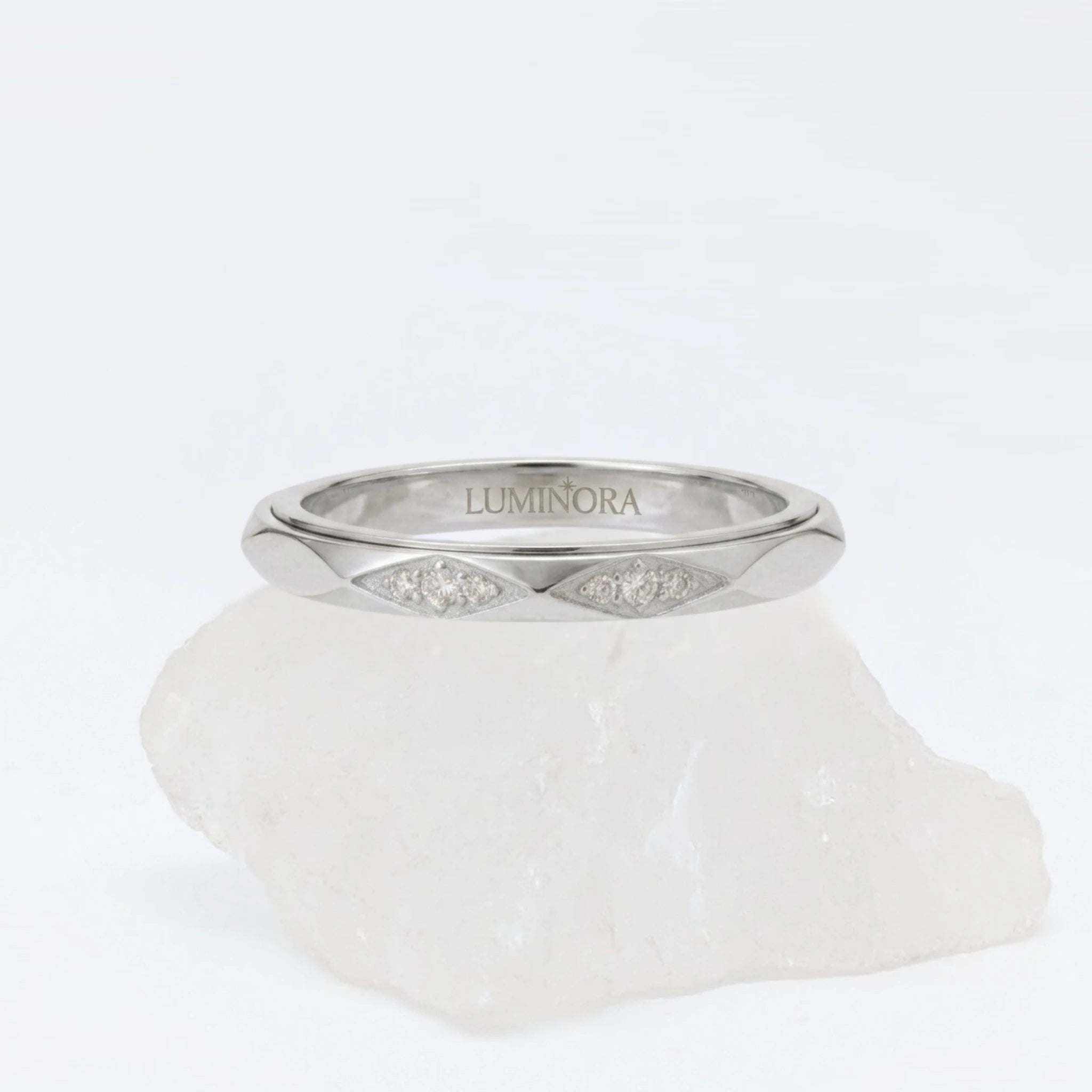 Zilveren Roa fidget ring van RVS met een roterend golfpatroon en subtiele zirkonia steentjes, gepresenteerd op een witte steen.