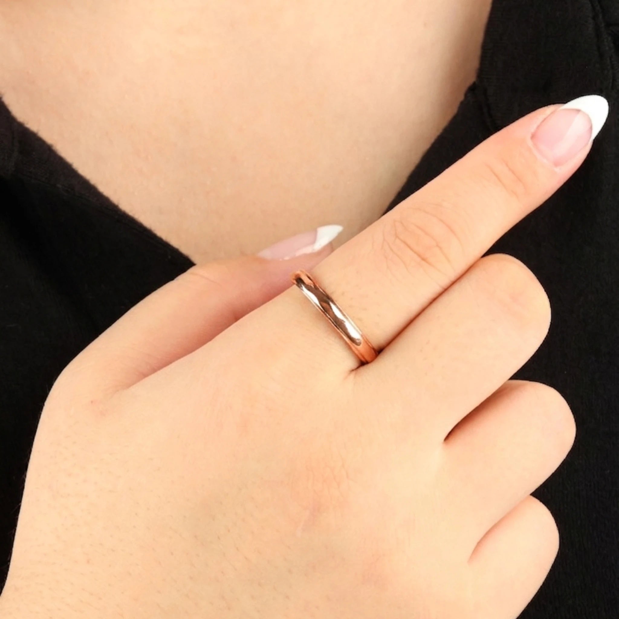 Roségouden Amara fidget ring met een gladde, subtiel golvende structuur, gedragen aan de wijsvinger van een model met een zwart topje.