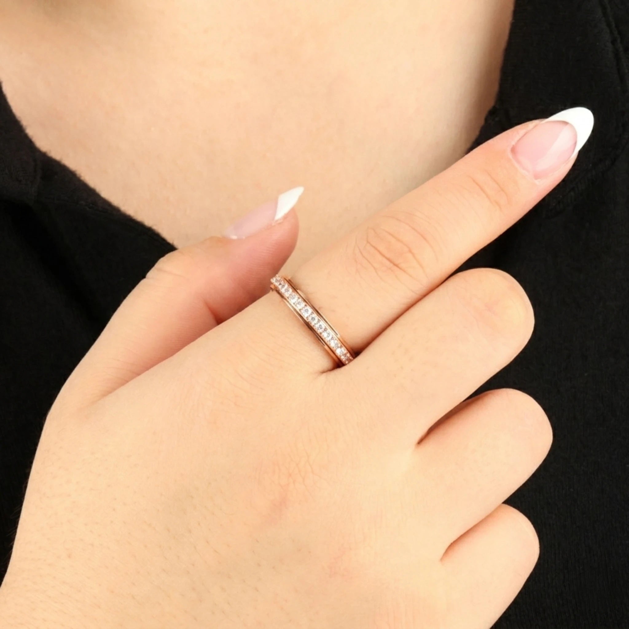 Minimalistische roségouden Haven fidget ring bezet met een rij subtiele glinsterende steentjes, gedragen aan de wijsvinger van een model met een zwart topje.