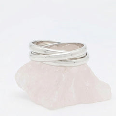 Zilveren Trinity fidget ring van RVS met drie in elkaar gehaakte, rollende ringen, gepresenteerd op een witte steen.