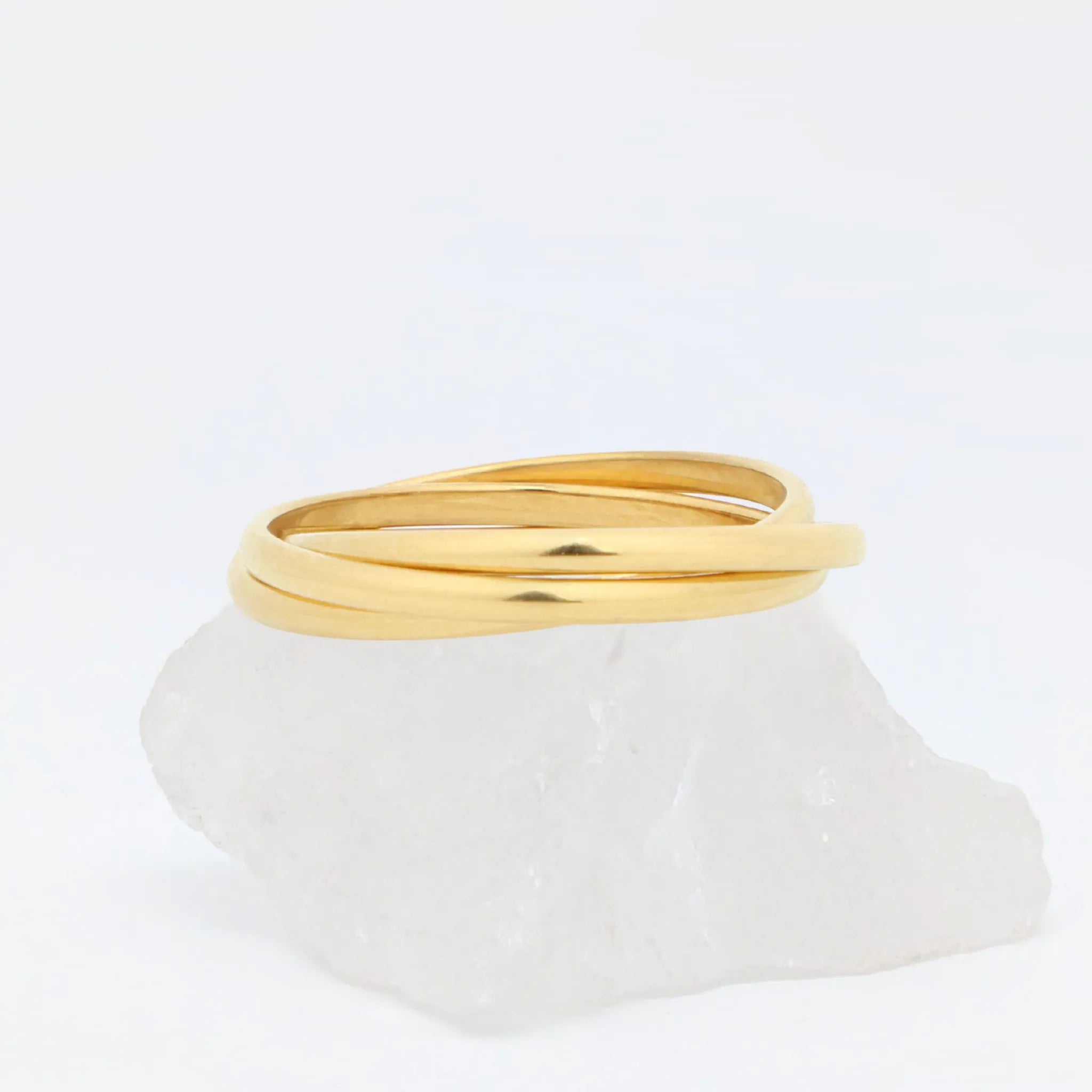 Gouden Unity fidget ring met drie vloeiende ringen op witte steen – Luminora
