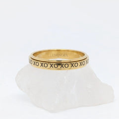 Gouden XO fidget ring van RVS met een roterend XO-design, elegant rustend op een witte steen.