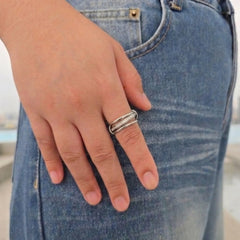 Zilveren Neo anti-stress ring met drie ringen en een draaibare steentjesband om de vinger, gefotografeerd tegen een blauwe spijkerbroek.