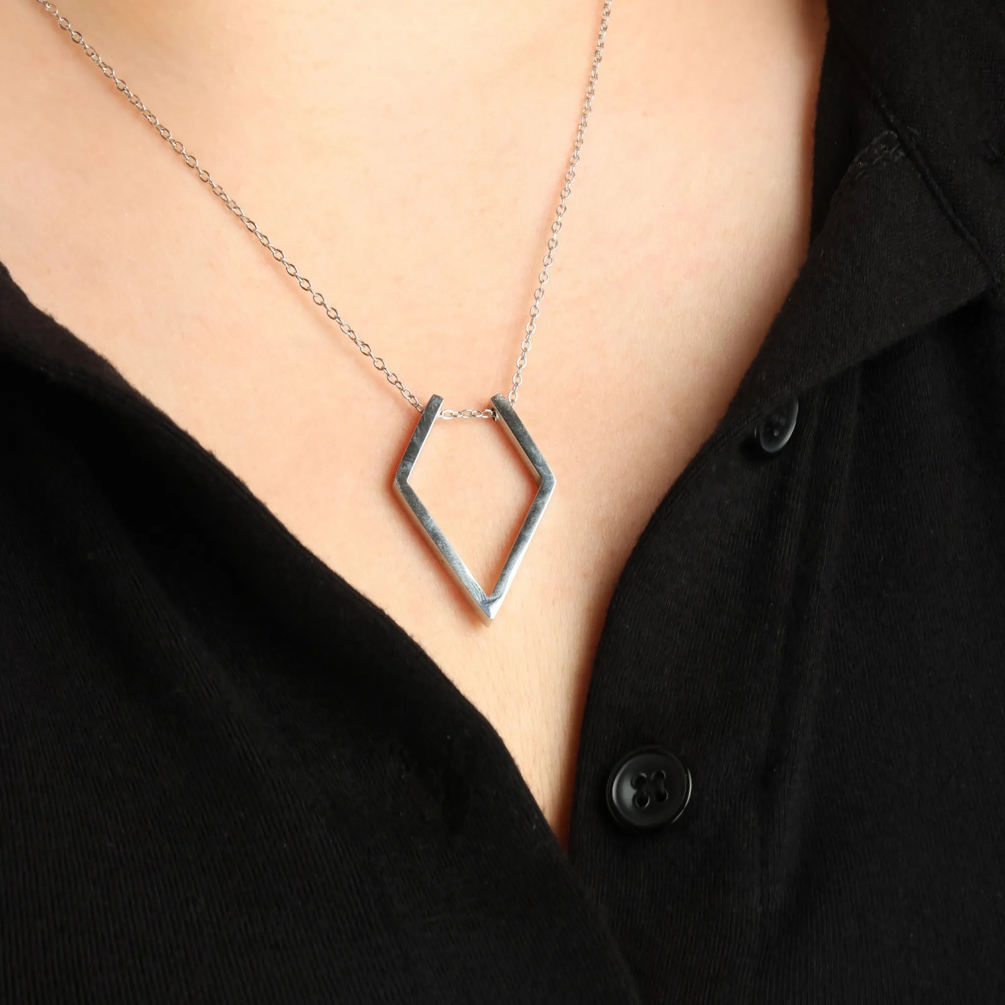 Zilveren Ring Keeper ketting van RVS rond de hals van een model met een zwart topje.